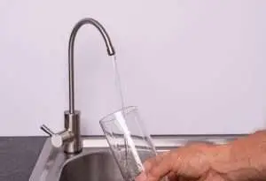 hand pouring a glass of water from a RO tap