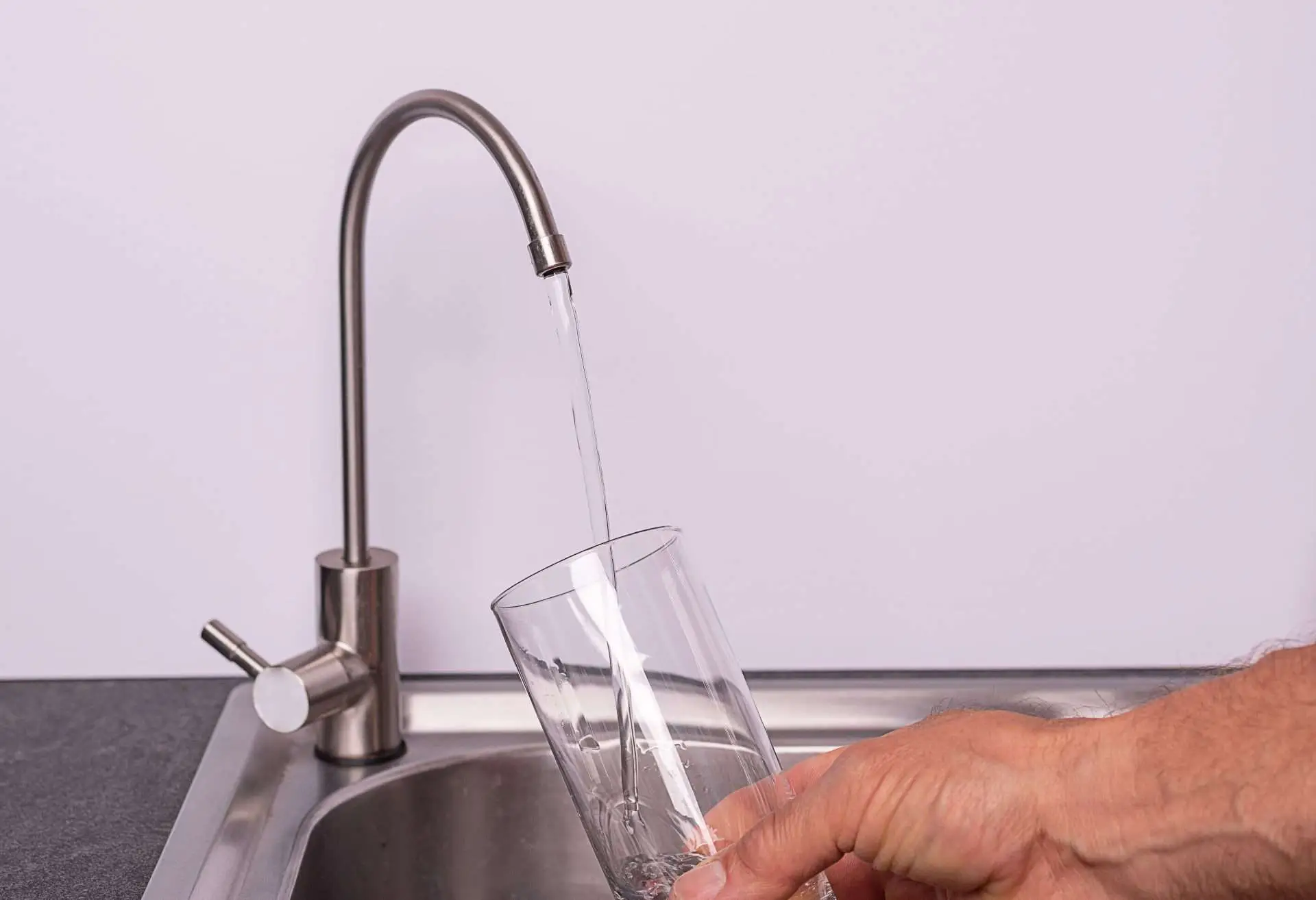 hand pouring a glass of water from a RO tap